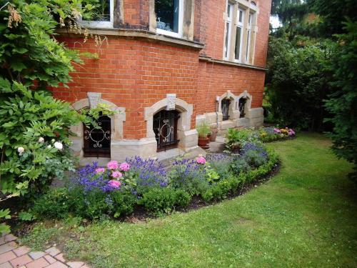a garden in front of a brick house with flowers at Ferienwohnung Markert in Blankenburg