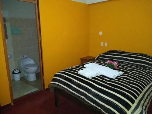 a bathroom with a bed with towels and a toilet at Hostal Lucky Puno in Puno