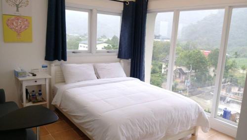a bedroom with a white bed and a large window at 梅花湖 轉角民宿 in Dongshan