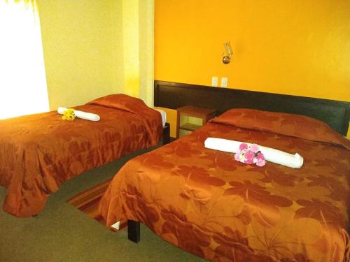 two beds in a hotel room with flowers on them at Hostal Lucky Puno in Puno