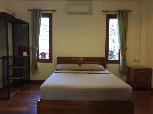 a bedroom with a bed and two windows at Pai Loess Resort in Pai