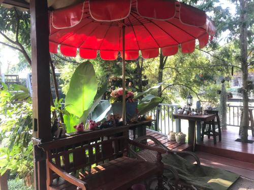 a porch with a red umbrella and a bench at Pai Loess Resort in Pai
