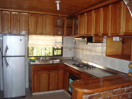 cocina con armarios de madera y nevera blanca en Cabañas Villa del Dorado, en Paipa