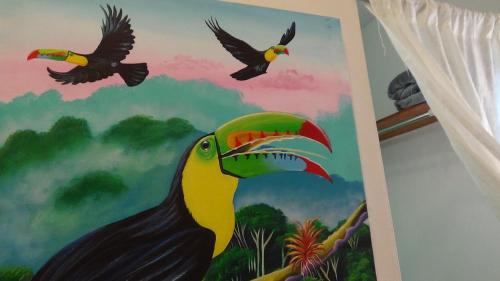 a painting of a toucan on a wall with two birds at Hacienda Tropical Guest House in Belmopan