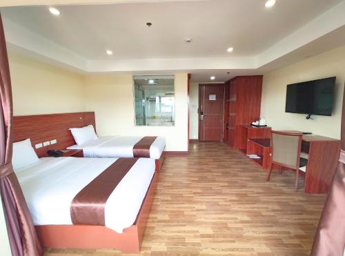 a hotel room with two beds and a flat screen tv at 456 Hotel in Baguio