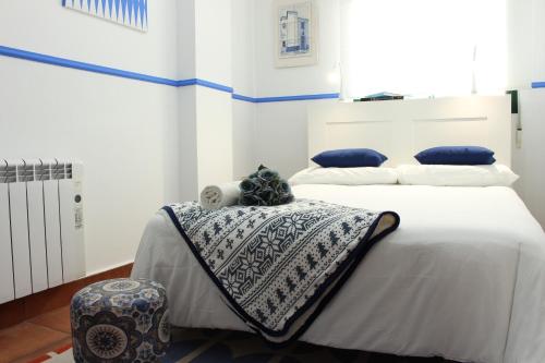 a bedroom with a white bed with blue pillows at Casa Rialto in Olivenza