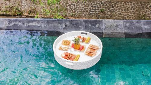 a white table with food on it next to a swimming pool at The Paica in Denpasar