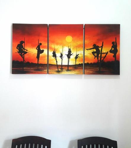 four paintings on a wall above two chairs at SunRay Rest - Beach View Homestay in Mirissa