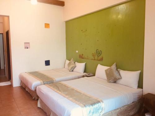 two beds in a room with a green wall at Morpheus B&B in Kenting