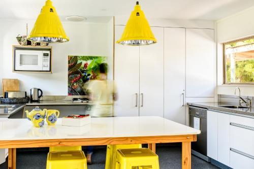 a kitchen with yellow chairs and a wooden table at Abel Tasman Lodge in Marahau