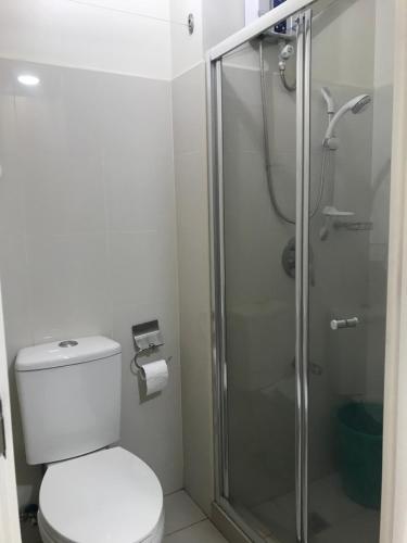 a bathroom with a toilet and a glass shower at Tagaytay Family vacation condo unit wind residences in Tagaytay