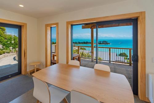 a dining room with a table and views of the ocean at Haulashore Vista in Nelson