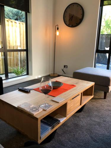 a wooden coffee table with a glass of wine on it at Coronet Haven in Queenstown