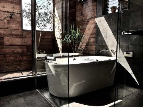 a bathroom with a tub and a glass shower at Guest House maison de stuffmarket in Takamatsu