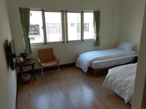 um quarto com uma cama, uma cadeira e janelas em Li Yuan Homestay em T'ien-chung