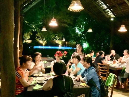 a group of people sitting at tables in a restaurant at A4 Villa & Spa. in Habarana