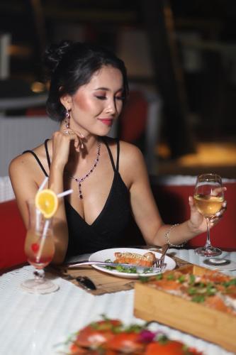 a woman sitting at a table with a plate of food at Queenco Hotel & Casino in Sihanoukville