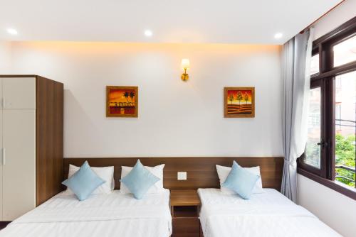 two beds in a room with a window at Bill Ben Homestay Hoi An in Hoi An