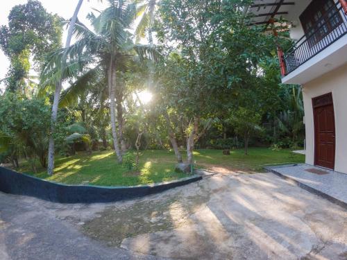 a driveway of a house with a yard with palm trees at Villa Girilena in Hikkaduwa