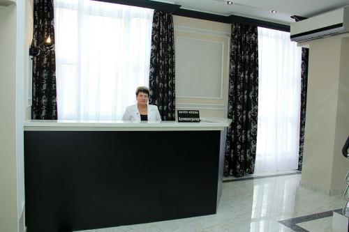 a woman is sitting at a reception desk at Estet Hotel in Essentuki