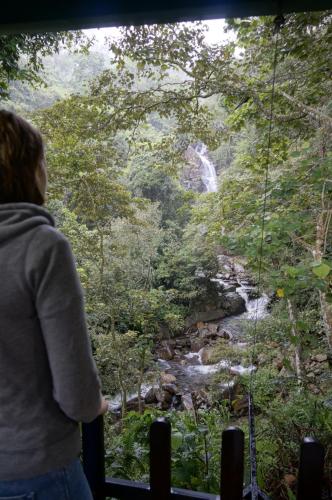 a woman standing on a suspension bridge looking at a waterfall at Sinharaja Kurulu Ella Eco Resort in Deniyaya