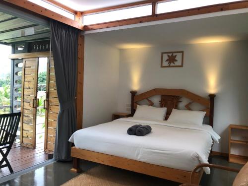 a bedroom with a white bed with a wooden headboard at Baan Boom Boxes Eco Friendly Resort in Mae Nam