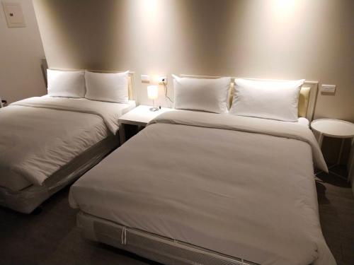 a hotel room with two beds with white pillows at In Fengchia in Taichung