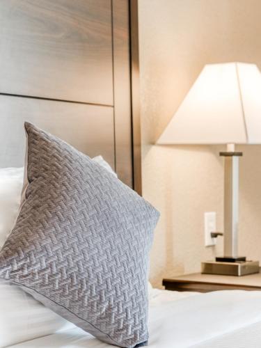 a pillow sitting on a bed next to a lamp at Alexis Hotel & Banquets Dallas Park Central Galleria in Dallas