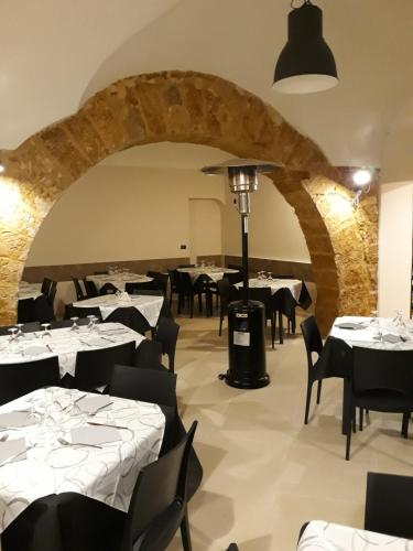 un ristorante con tavoli bianchi e sedie nere di Palazzo Russo a Ribera