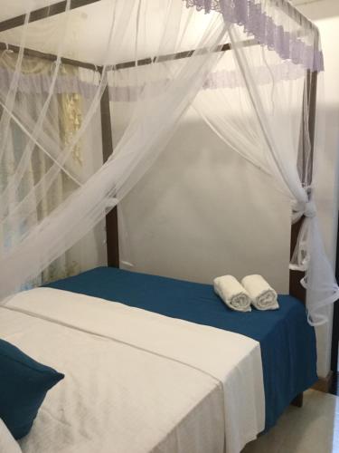 a bedroom with a bed with a canopy and two towels at Sea Close Inn in Ahangama