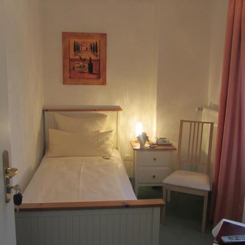 a small bedroom with a bed and a chair at Hotel Angermeier GARNI in Eching