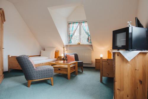 a room with a bed and a tv and chairs at Hotel Angermeier GARNI in Eching