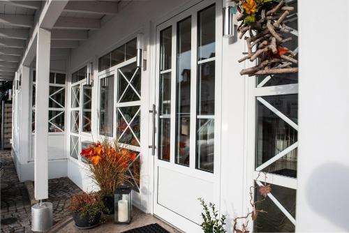 a white front door of a house with plants at Hotel Angermeier GARNI in Eching