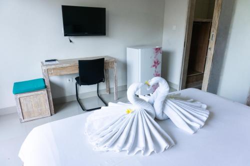 two white swans are sitting on a bed at Matra Co Working & Co Living in Canggu