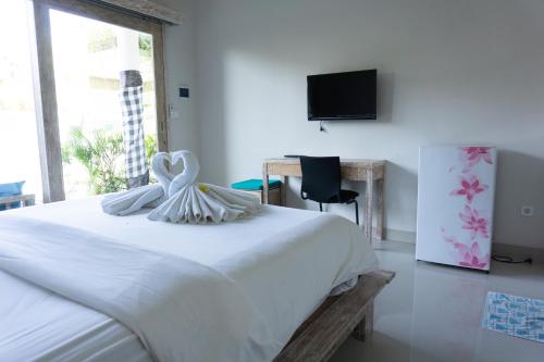 a white bed in a room with a tv at Matra Co Working & Co Living in Canggu