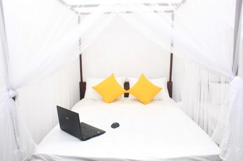 a bedroom with a laptop on a bed with curtains at Hotel BEJEWELLED Sigiriya in Sigiriya