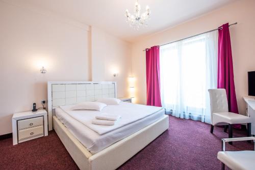 Hotel Imperial Premium في تيميشوارا: غرفة نوم بسرير أبيض وستائر وردية