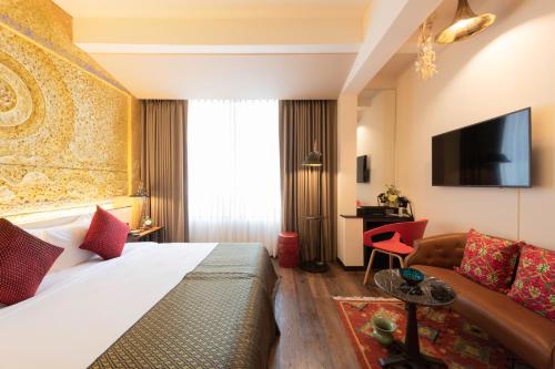 バンコクにあるDhevi Bangkok Hotelのベッドとソファ付きのホテルルーム