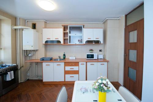 una cocina con armarios blancos y una mesa con flores en Stephanie Apartment-Centru civic, en Brasov
