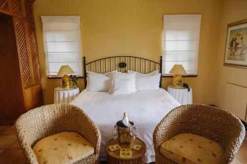 a bedroom with a bed with two wicker chairs at High Timbers Lodge in Tokai