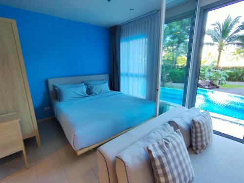 a blue bedroom with a bed and a large window at BLU-Pool Access in Cha Am