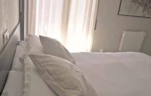 a white bed with white pillows and a window at Hotel Esteba in Caldes de Malavella