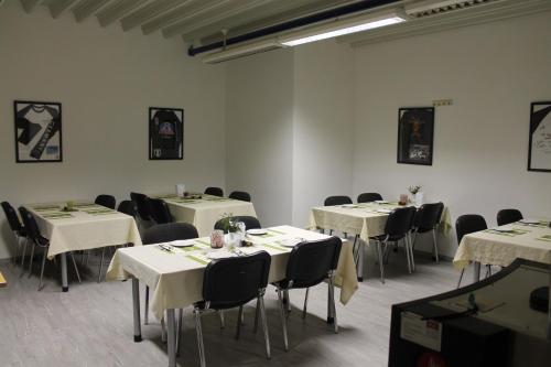 ein Zimmer mit Tischen und Stühlen mit weißen Tischdecken in der Unterkunft Pension Take Off in Gera