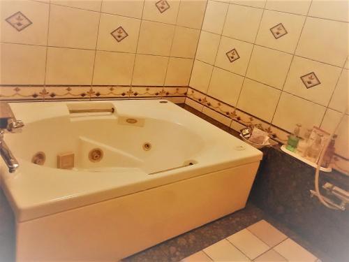 a bath tub in a bathroom with a tile wall at Hotel Route One in Osaka