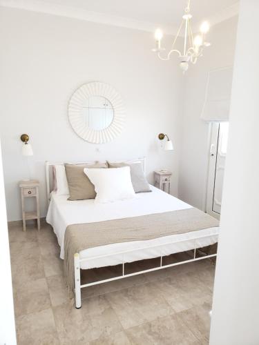 ein weißes Schlafzimmer mit einem weißen Bett und einem Spiegel in der Unterkunft Anthi's view in Karpathos
