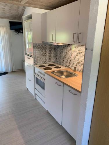 a kitchen with white cabinets and a sink at Ristinge Ferielejligheder in Humble