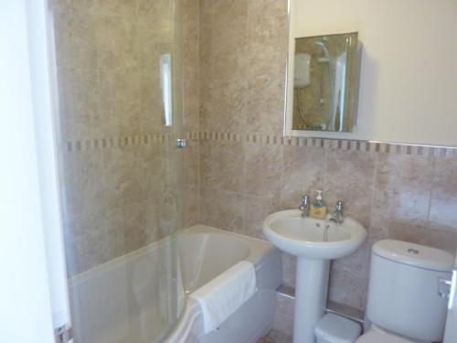 łazienka z wanną, umywalką i toaletą w obiekcie Ocean's Edge w mieście Perranporth