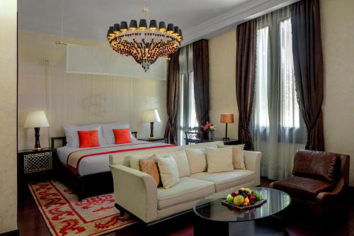 a hotel room with a bed and a couch and a chandelier at Sofitel Legend Old Cataract in Aswan