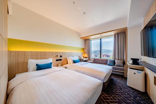 2 łóżka w pokoju hotelowym z dużym oknem w obiekcie Keio Prelia Hotel Sapporo w mieście Sapporo