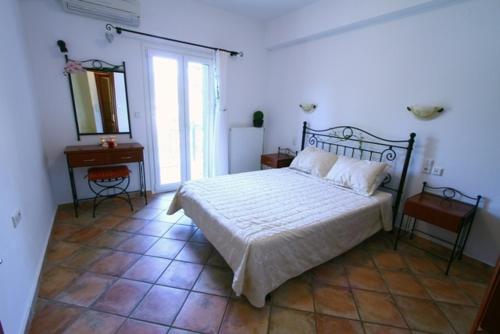1 dormitorio con cama, mesa y espejo en Villa Polyxeni Apartments, en Sivota
